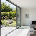 Porte-fenêtre coulissante en aluminium ouverte sur un jardin lumineux.